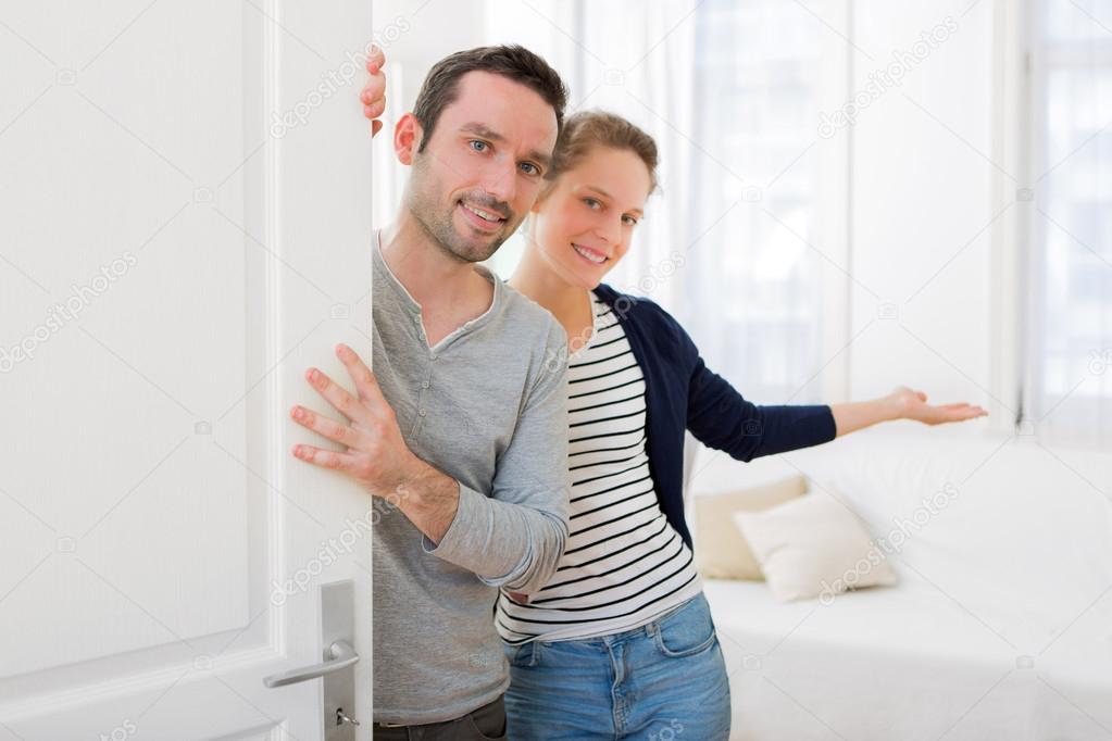 Young attractive couple welcoming you in his house