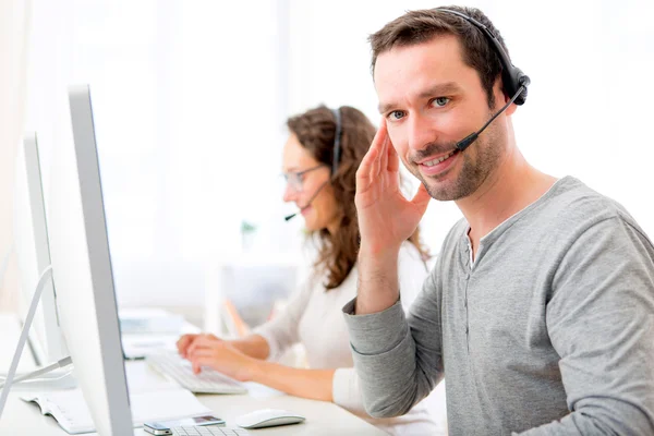 Jovem homem atraente trabalhando em um call center — Fotografia de Stock