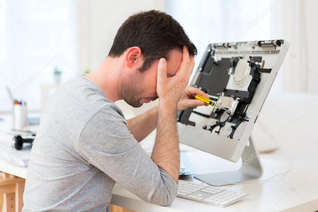 Young attractive man trying to repair computer