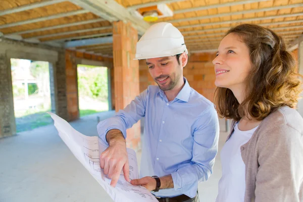 Mujer joven y arquitecto en obra — Foto de Stock