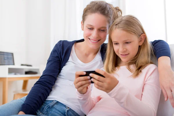 Attractive woman and little sister using mobile — Stock Photo, Image