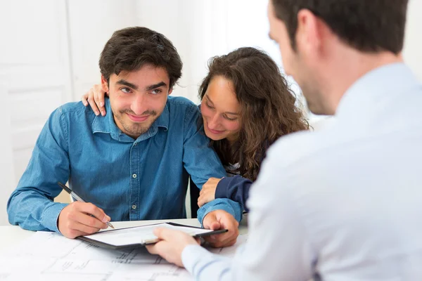 Young attractive couple signing contract — Stock Photo, Image