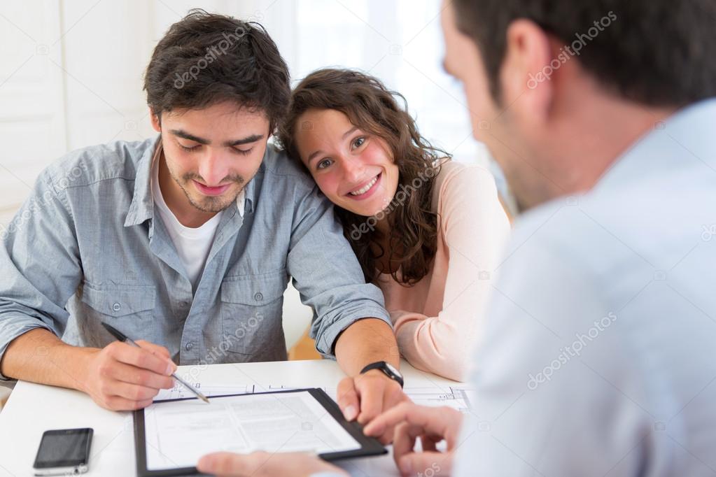 Young attractive couple signing contract