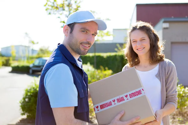 Delivery man handing over a parcel to customer — Stock Photo, Image