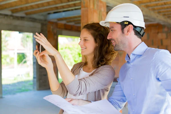 Mujer joven y arquitecto en obra — Foto de Stock