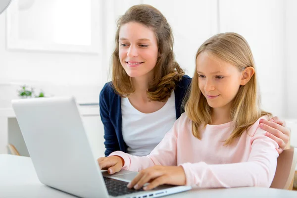 Attractive woman and little sister using laptop — Stock Photo, Image