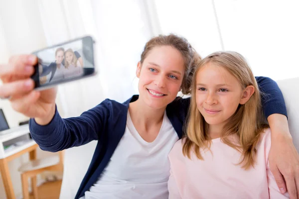 Mulher atraente e irmãzinha tomando selfie — Fotografia de Stock