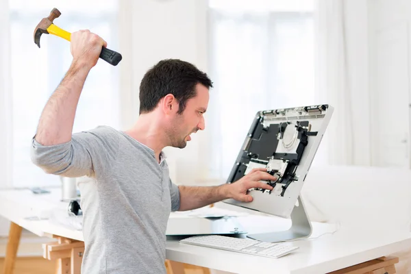 Young attractive man angry against computer — Stock Photo, Image