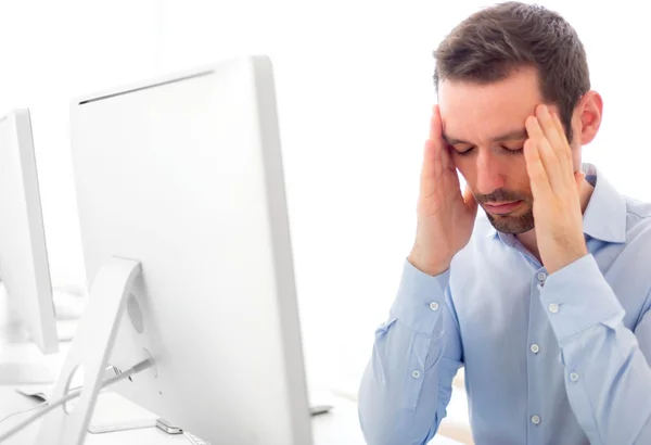 Joven atractivo hombre tiene un dolor de cabeza en la oficina —  Fotos de Stock