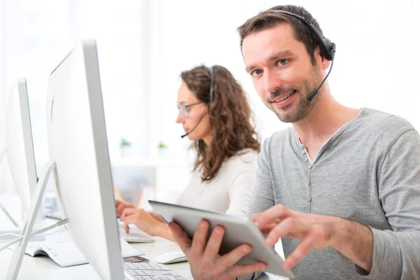 Junger attraktiver Mann, der in einem Callcenter arbeitet — Stockfoto