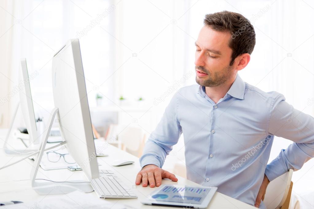 Young attractive man got a back pain at the office