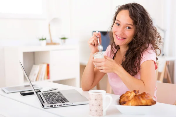 Joven estudiante atractivo tomando el desayuno mientras trabaja —  Fotos de Stock