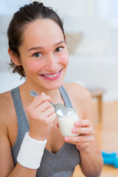 Привлекательная спортивная женщина ест йогурт после занятий спортом — стоковое фото