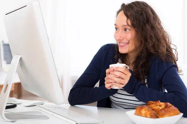 Jeune étudiant attrayant prenant le petit déjeuner tout en travaillant — Photo