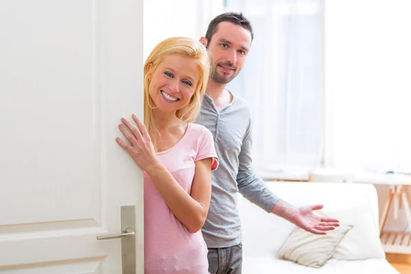 Jovem casal atraente recebê-lo em sua casa — Fotografia de Stock