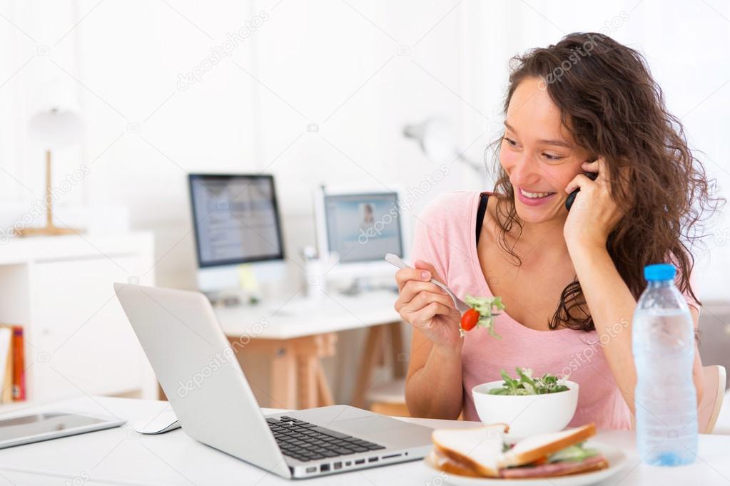 Young attractive student eating salad while phoning