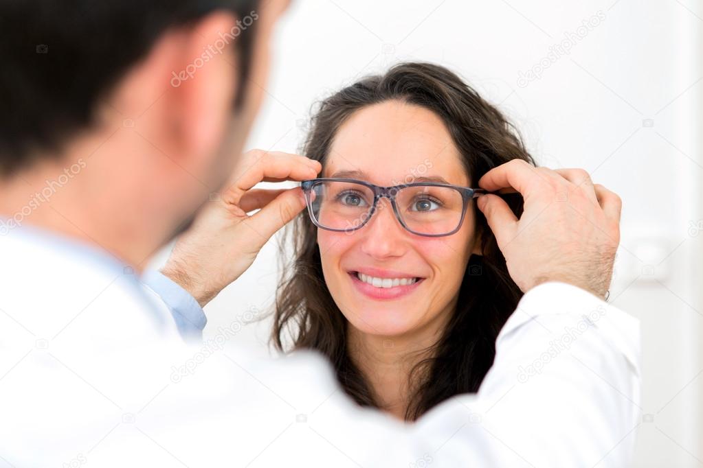 Young attractive woman trying glasses w optician