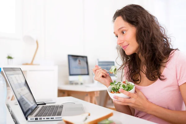 Ung attraktiv student äta sallad medan du arbetar — Stockfoto
