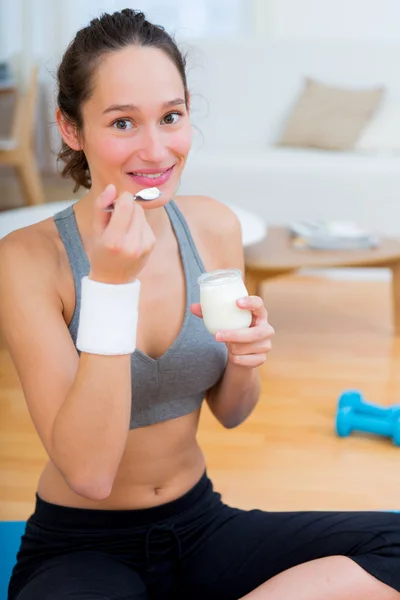 Attractive sportive woman eating yoghurt after sport