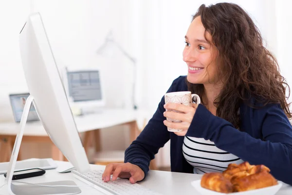 Jeune étudiant attrayant prenant le petit déjeuner tout en travaillant — Photo