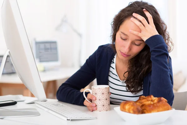 Junger müder Student frühstückt während der Arbeit — Stockfoto