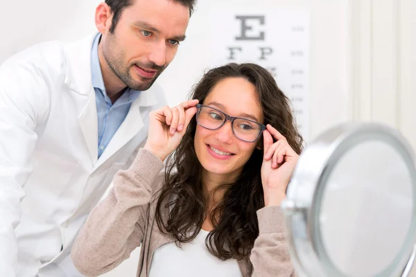 Opticida ajudando uma mulher a escolher óculos — Fotografia de Stock