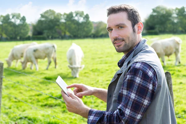 Giovane agricoltore attraente che utilizza tablet in un campo — Foto Stock