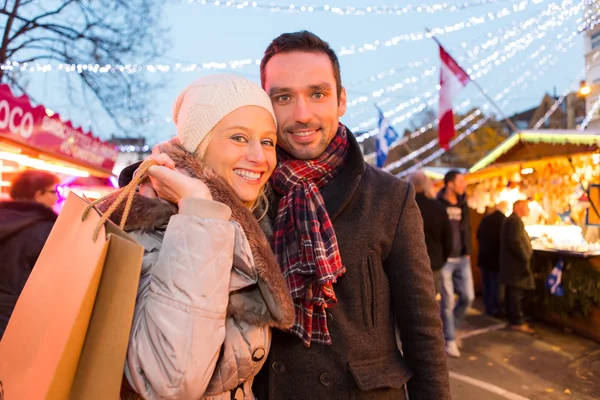 Young attractive couple in a christmas market — Stock Photo, Image