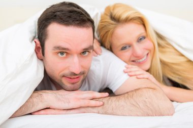 Mutlu genç bir çift bir yatakta portresi