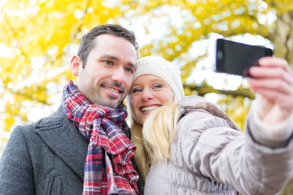 Jeune couple attrayant prenant selfie dans un parc — Photo