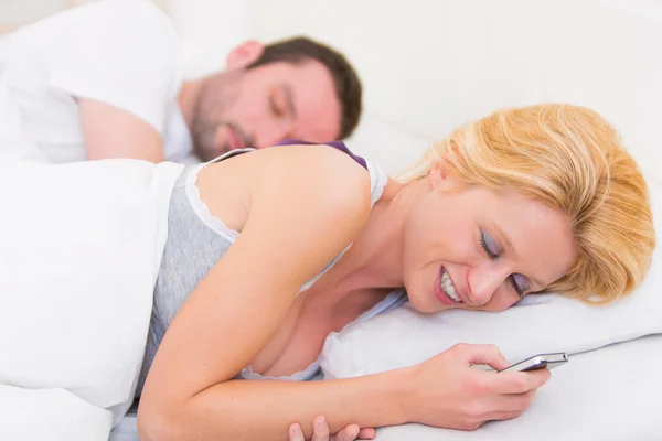 Junge attraktive Frau sendet Text in einem Bett — Stockfoto