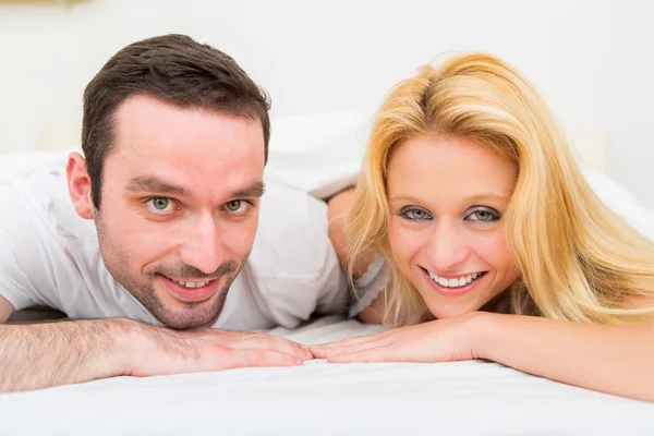 Retrato de um jovem casal feliz em uma cama — Fotografia de Stock