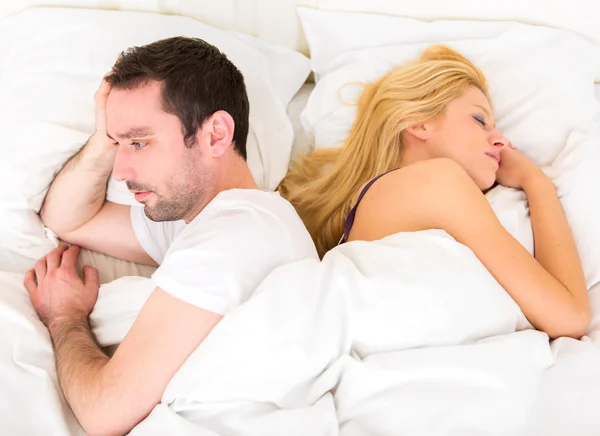 Junge attraktive nachdenkliche Mann in einem Bett — Stockfoto