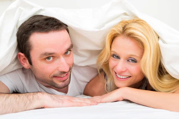 Retrato de um jovem casal feliz em uma cama — Fotografia de Stock