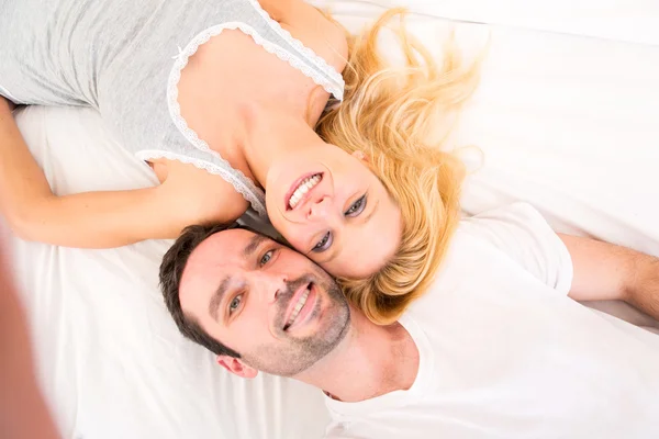 Young attracttive couple taking selfies in bed — Stock Photo, Image