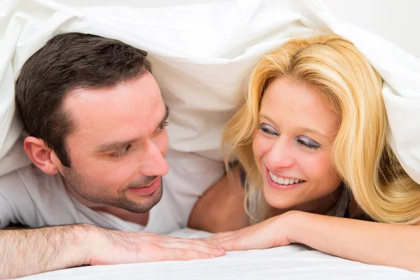 Retrato de um jovem casal feliz em uma cama — Fotografia de Stock