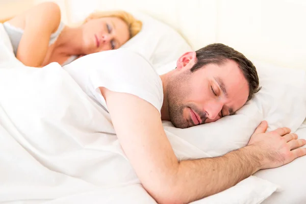 Joven pareja atractiva durmiendo en una cama — Foto de Stock