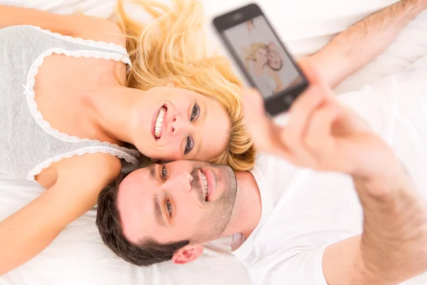 Young attracttive couple taking selfies in bed — Stock Photo, Image