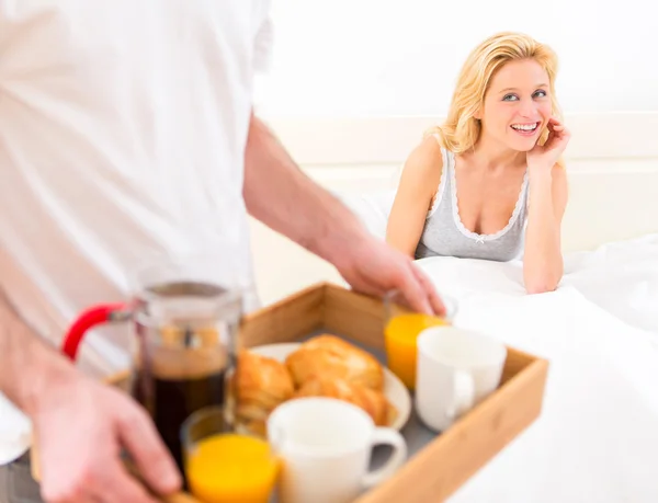 Man bringing young attractive woman breakfast in bed Stock Picture