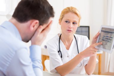 Genç Doktor hastaya tablet üzerinde gösterilen sonuçlar