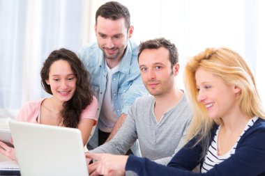 4 genç çekici insanların bir dizüstü bilgisayarda çalışma grubu