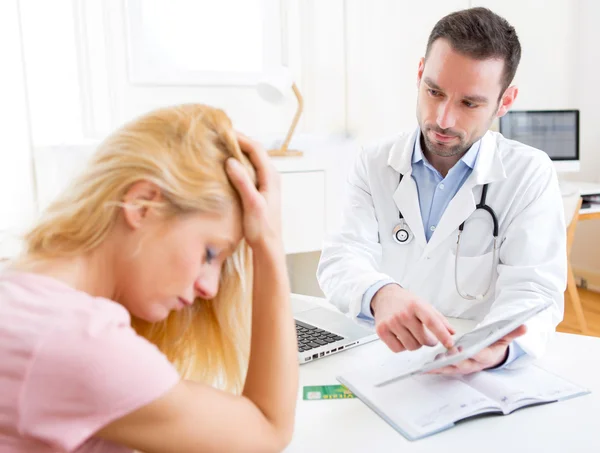 Médico jovem mostrando resultados em comprimido para paciente — Fotografia de Stock