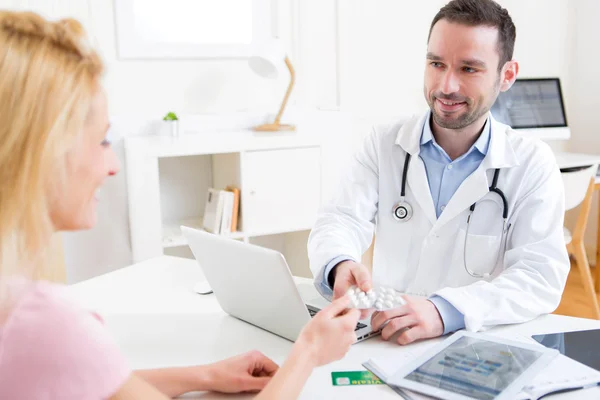 Jonge aantrekkelijke dokter pillen om een patiënt — Stockfoto