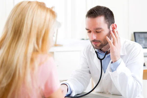 Giovane uomo attraente che ascolta nel suo stetoscopio — Foto Stock