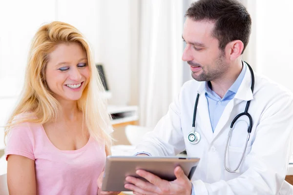 Unga läkare visar resultaten på tablett till patient — Stockfoto