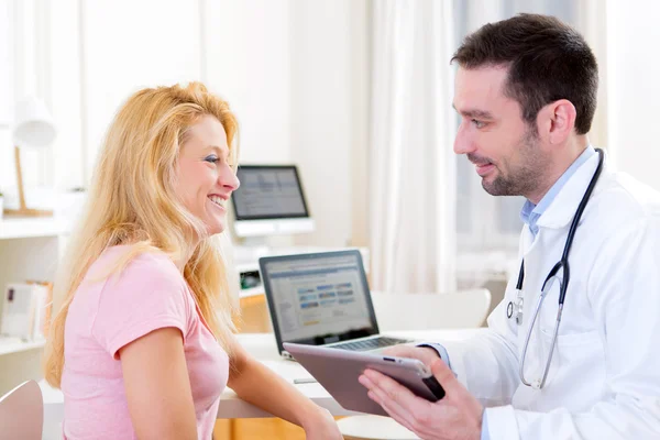 Young doctor showing results on tablet to patient — Stock Photo, Image