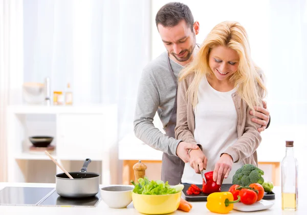 Young attractive man helping out his wife while cooking — Stock Photo, Image