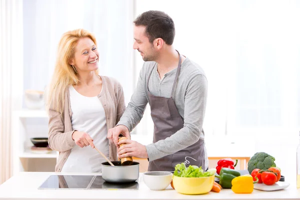 Jovem homem atraente ajudando sua esposa enquanto cozinha — Fotografia de Stock