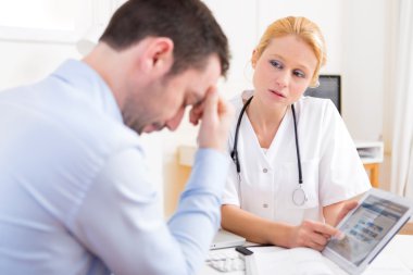 Genç Doktor hastaya tablet üzerinde gösterilen sonuçlar