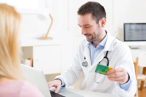 Joven médico atractivo tomando tarjeta de seguro de salud —  Fotos de Stock